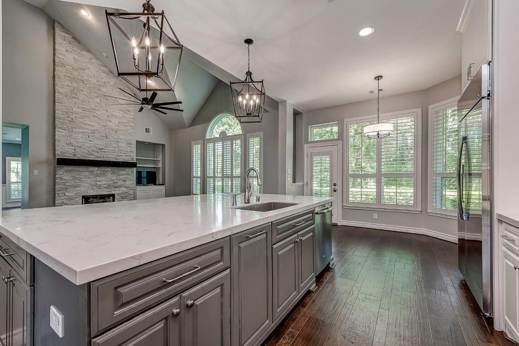 a modern white and gray kitchen with a stone island and custom installed windows