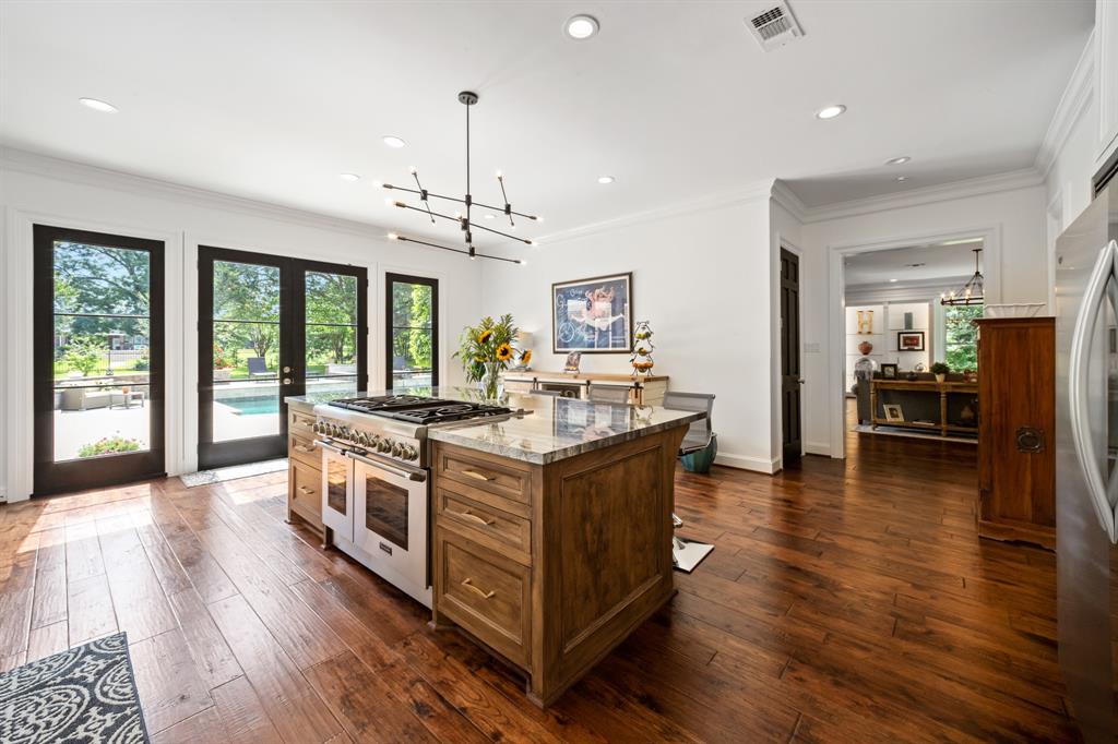 a modern kitchen with a polished stone island and large picture windows and patio doors 