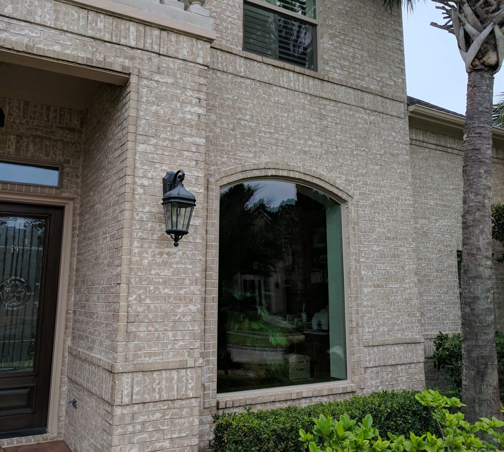 Eco-Friendly Windows for a Greener Houston Home Exterior view of brick house with large arched picture window.
