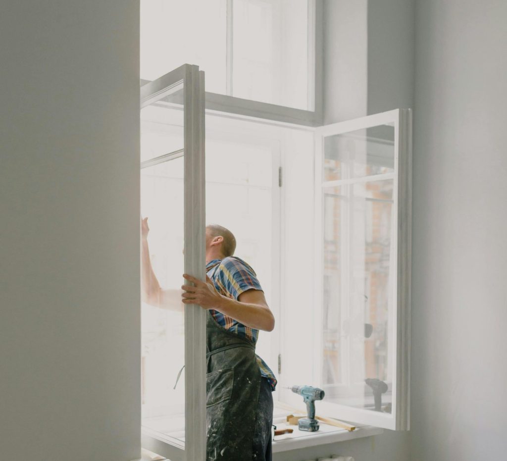 Unrecognizable workman installing window in new apartment.