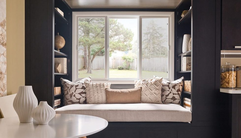A sliding bay window area decorated with cushions and modern decor.