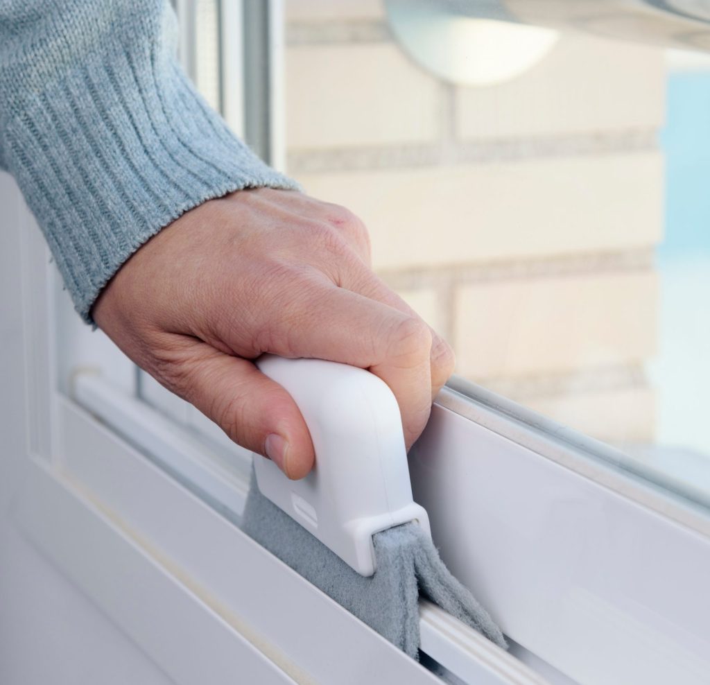 Man Cleaning The Grooves Of A White Aluminum Sliding Window